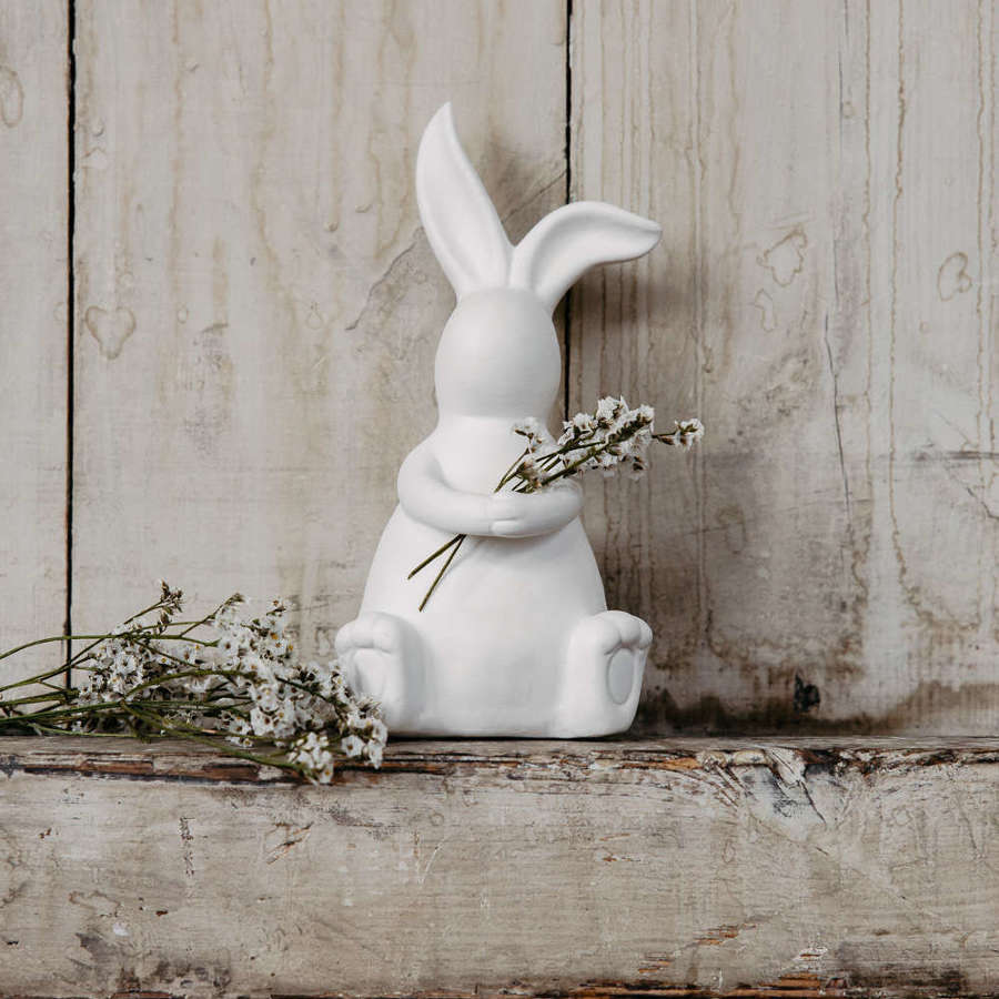 Large white ceramic bunny with hands clasped